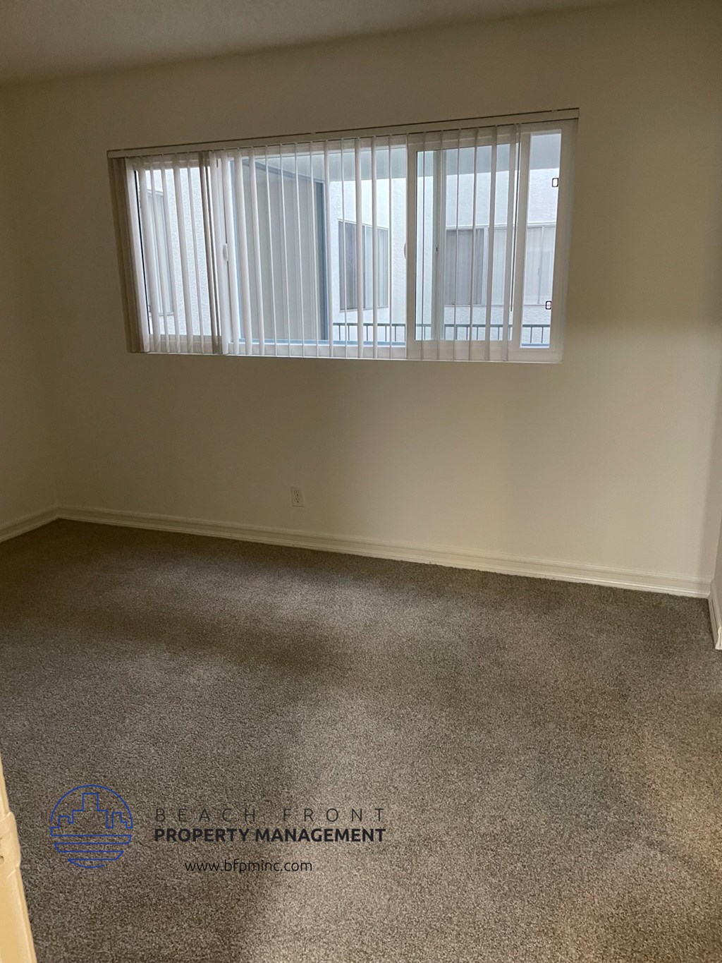 an empty room with a window and a carpet floor